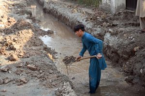Laborer busy digging for installing pipelines on main commercial market road in the city
