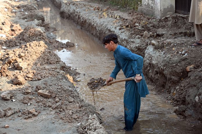 Laborer busy digging for installing pipelines on main commercial market road in the city