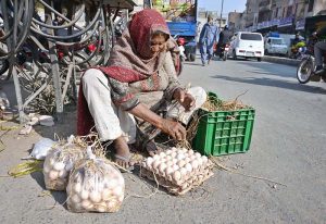 An elderly woman arranging eggs to attract customers at her roadside setup in Muslim Bazaar.