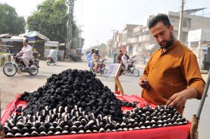 A vendor busy arranging and displaying fresh Singhara (water chestnuts) on his handcart to attract customers at a roadside stall.