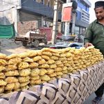 A vendor displaying traditional sweet item (Gurr) on his cart at College Road