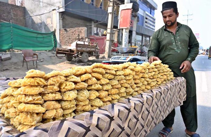 A vendor displaying traditional sweet item (Gurr) on his cart at College Road