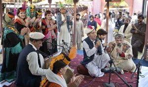 A young artisan shapes clay into small pots on a pottery wheel with the guidance of a potter during the Ten-Day annual folk festival “Lok Mela 2025” at Lok Virsa.