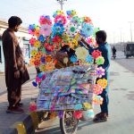 A roadside vendor displays colourful paper pinwheels to attract customers along General Bus stand road