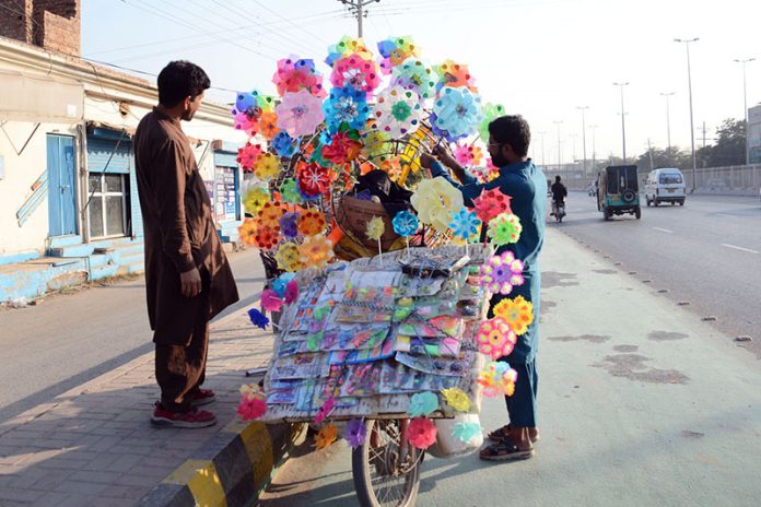 A roadside vendor displays colourful paper pinwheels to attract customers along General Bus stand road