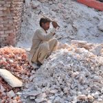 A worker is busy crushing salt for packaging at his workplace.