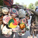 A vendor displays traditional handmade kitchen items on his bike along the roadside