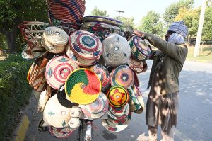 A vendor displays traditional handmade kitchen items on his bike along the roadside