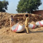 Workers weigh large sacks filled with husk from wheat at a storage site on the outskirts of the city