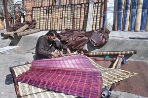 A skilled craftsman is busy making a beautiful traditional 'chick' bamboo curtain at his roadside setup at Chauburji Chowk.