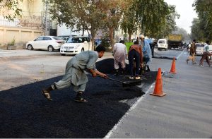 NHA workers repair a damaged section of Allama Iqbal Road to ensure the smooth flow of traffic in the city.