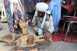An artist making traditional music instrument Rubab at his stall during the ten-day annual folk festival “Lok Mela 2025” at Lok Virsa.