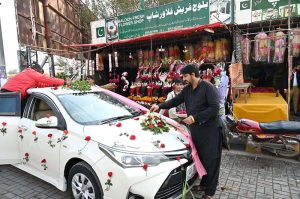 Floral shop vendors decorate a bride and groom’s car with fresh roses, flowers and ribbons at 47 Adda as the wedding season begins in the city.