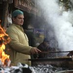 A cook grills fresh BBQ, drawing visitors with its tempting aroma during the ten-day annual folk festival “Lok Mela 2025” at Lok Virsa.