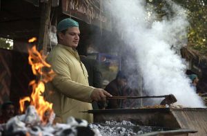 A cook grills fresh BBQ, drawing visitors with its tempting aroma during the ten-day annual folk festival “Lok Mela 2025” at Lok Virsa.