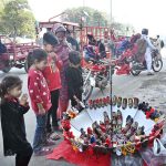 A woman along with children keenly watching children shoes beautifully decorated in umbrella at a roadside stall in the Provincial Capital.