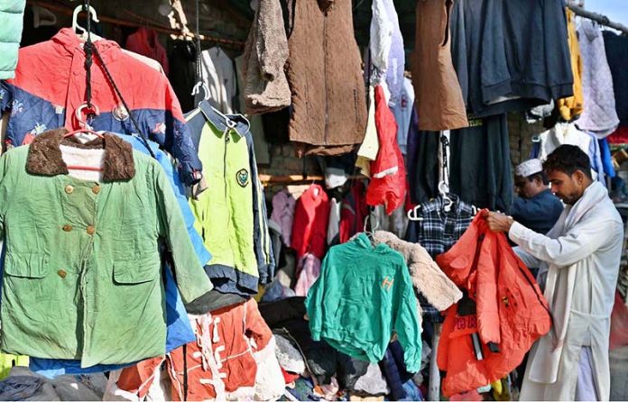 People browse and purchase warm clothing at a roadside stall on Old Bus Stand Road amid the onset of winter