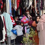 Women select and purchase clothes at the G-9 weekly bazaar in the Federal Capital
