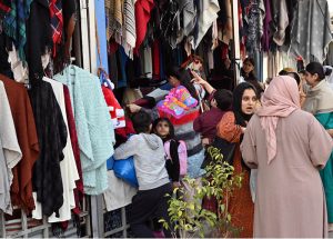 Women select and purchase clothes at the G-9 weekly bazaar in the Federal Capital