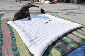 A worker is busy stitching a quilt for a customer at his workplace in Sector G-7 of the Federal Capital
