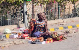 A woman vendor arranging and displaying bangles to attract customers at her roadside setup.