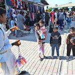 A vendor make water bubbles with a toy gun to attract children at H-9 weekly bazaar in Federal Capital
