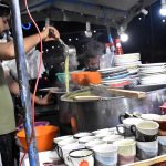 A vendor serves steaming hot chicken corn soup to customers as the winter chill boosts demand for warming street foods across the city