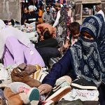 Women are busy in selecting and purchasing second hand shoes from vendor during upcoming winter season at outside cloth market road