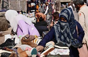 Women are busy in selecting and purchasing second hand shoes from vendor during upcoming winter season at outside cloth market road