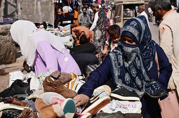 Women are busy in selecting and purchasing second hand shoes from vendor during upcoming winter season at outside cloth market road