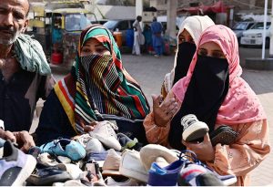 Women are busy in selecting and purchasing second hand shoes from vendor during upcoming winter season at outside cloth market road