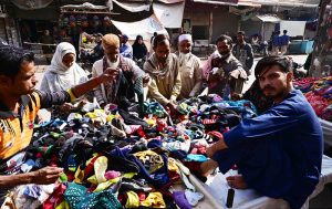 Women are busy in selecting and purchasing second hand shoes from vendor during upcoming winter season at outside cloth market road