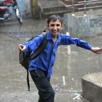 A schoolboy gets drenched while playing and splashing in the season’s first winter rain, celebrating the arrival of the chilly weather