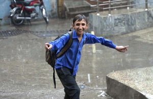 A schoolboy gets drenched while playing and splashing in the season’s first winter rain, celebrating the arrival of the chilly weather