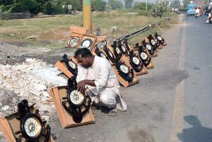 A vendor displays wall clocks to attract the customers at roadside setup.