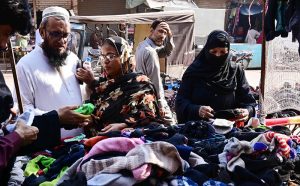 Women are busy in selecting and purchasing second hand shoes from vendor during upcoming winter season at outside cloth market road