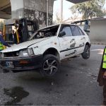 Police officials remove a damaged car from the spot of a suicide attack on the Federal Constabulary headquarters, where three FC soldiers were killed and 11 civilians injured
