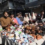 Shoppers browse and purchase shoes from a hand-carried vendor on a holiday in the city