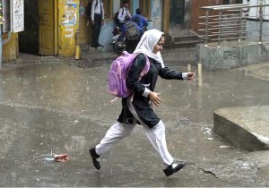 A schoolboy gets drenched while playing and splashing in the season’s first winter rain, celebrating the arrival of the chilly weather