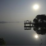 A serene afternoon scene at Rawal Lake in the federal capital, with the sun casting its reflection across the still water near a lakeside viewing platform