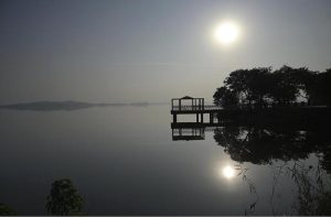 A serene afternoon scene at Rawal Lake in the federal capital, with the sun casting its reflection across the still water near a lakeside viewing platform