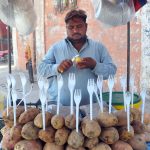 A vendor cutting sweet potatoes for the customers at his roadside setup