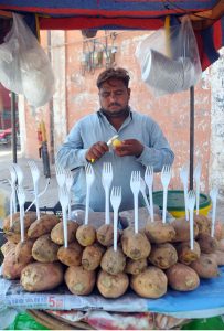 A vendor cutting sweet potatoes for the customers at his roadside setup