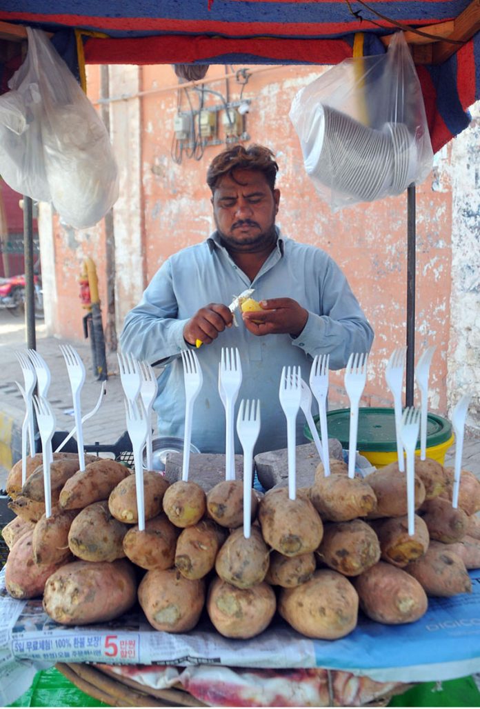 A vendor cutting sweet potatoes for the customers at his roadside setup
