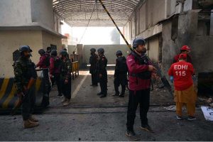 Police officials remove a damaged car from the spot of a suicide attack on the Federal Constabulary headquarters, where three FC soldiers were killed and 11 civilians injured