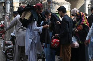 Shoppers browse and purchase shoes from a hand-carried vendor on a holiday in the city