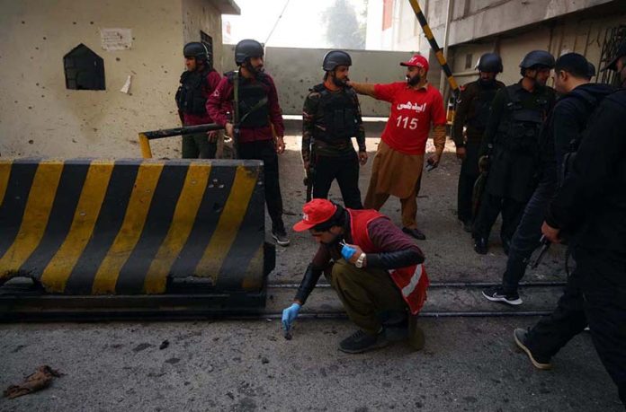 Rescue and security personnel collect evidence at the scene of a suicide attack on the Federal Constabulary headquarters, where three FC soldiers were killed and 11 civilians injured