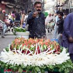 A vendor sells fresh vegetable salads from a hand-held cart, spraying water to keep them fresh in the city