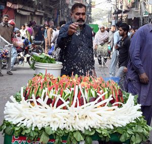 A vendor sells fresh vegetable salads from a hand-held cart, spraying water to keep them fresh in the city