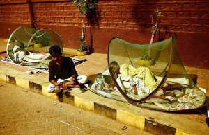 Gypsy families rest under a mosquito net on the footpath outside Radio Pakistan Road.